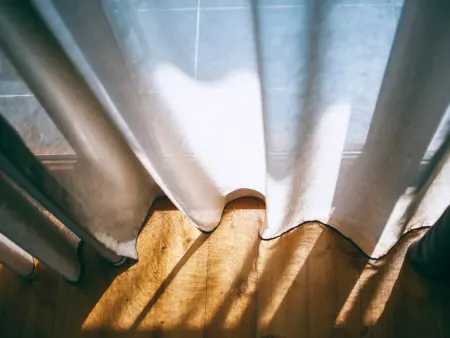 Morning coming through the curtain onto the floorboards.