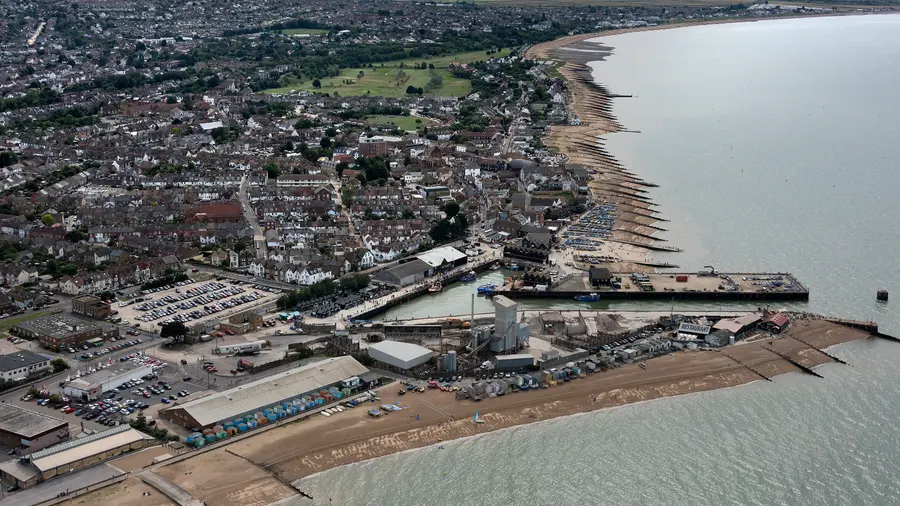Whitstable from the air: the town, the harbour, the working boats and the row of beach huts along the shore.