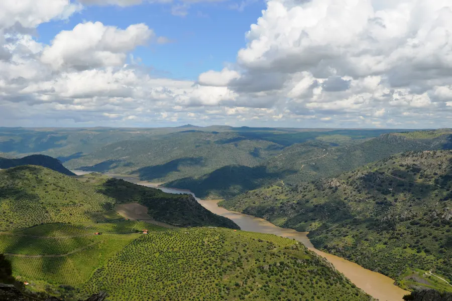 Um rio a serpentear por um vale de encostas verdes.