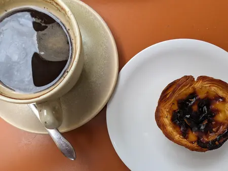 Um pastel de nata e uma bica no balcão.