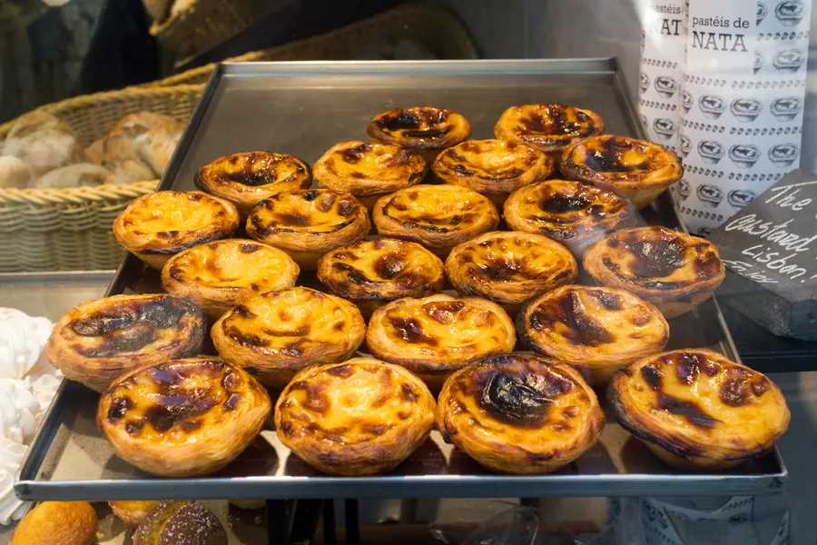 Pastéis de nata acabados de sair do forno, com o topo queimado e a massa ainda a estalar.