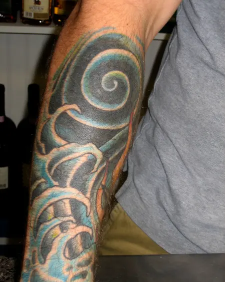 A forearm with a shaded swirl design in grey and teal.